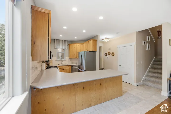 Kitchen with light wood cabinetry, stainless steel appliances, and a tiled backsplash