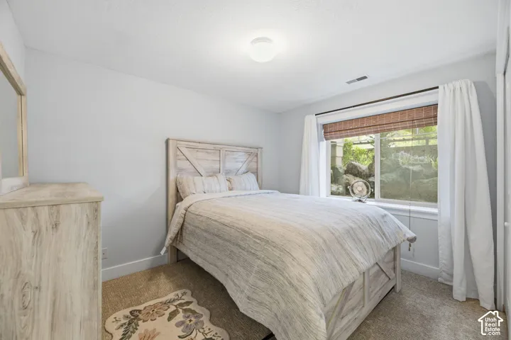 Light gray wall paint, recessed window with a woven wood shade, white window trim, and wall-to-wall carpeting