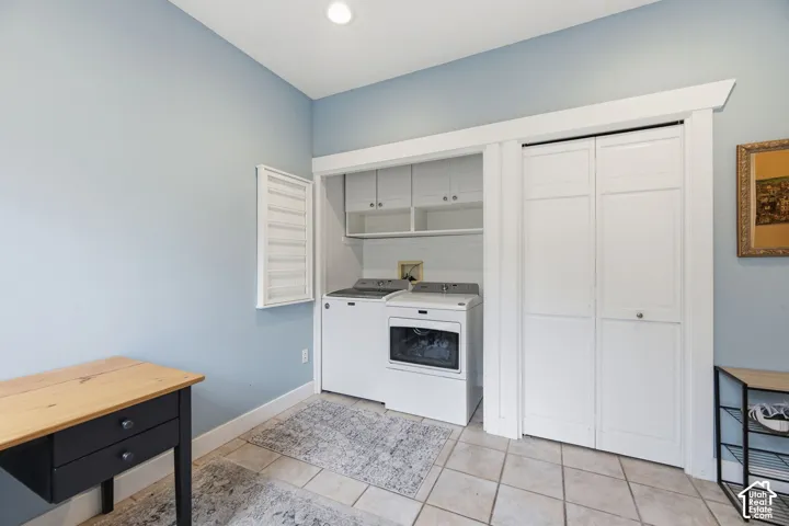 Integrated laundry area featuring white cabinetry, a built-in drying rack, and neutral tile flooring