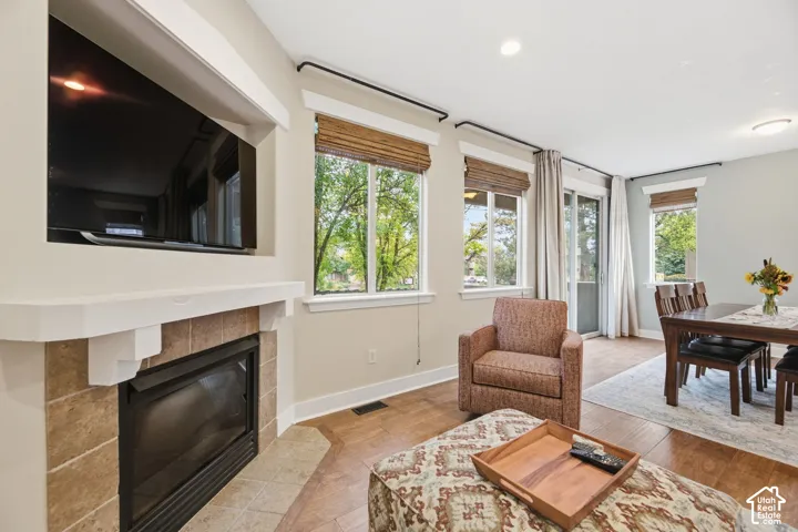 Fireplace with tile surround and white mantel, wood-finish flooring, recessed lighting, and a sliding glass door