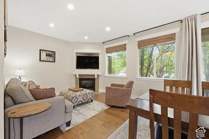 Wood-finish flooring, recessed lighting, and a corner fireplace with a tile surround and mantel