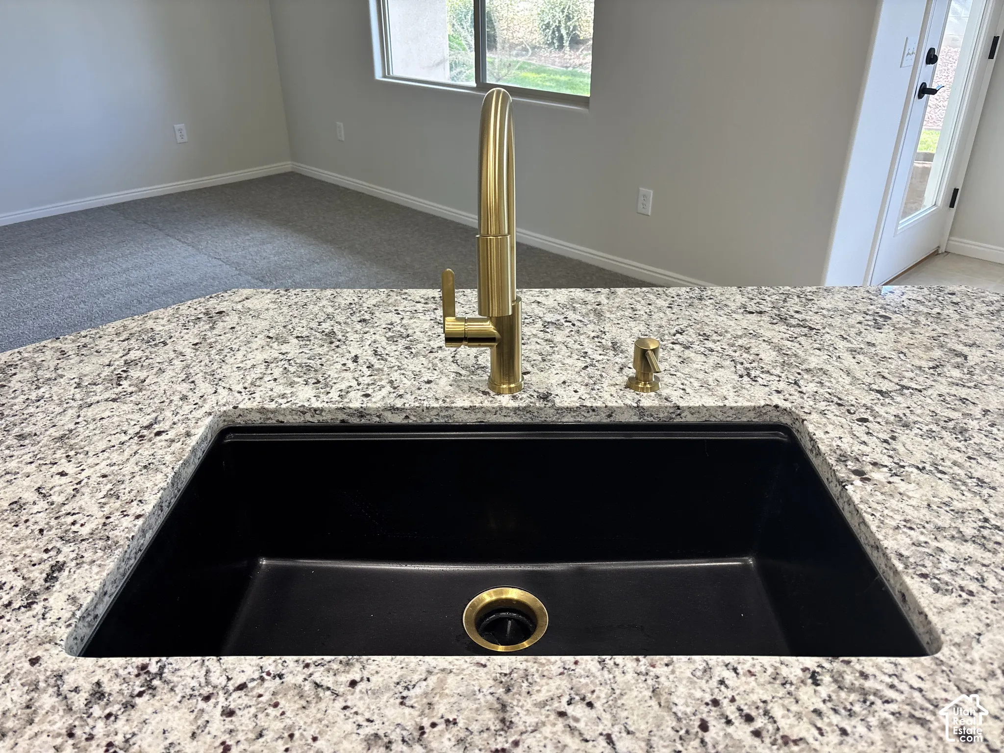 Granite-style countertop with an undermount black sink and gold-finish faucet