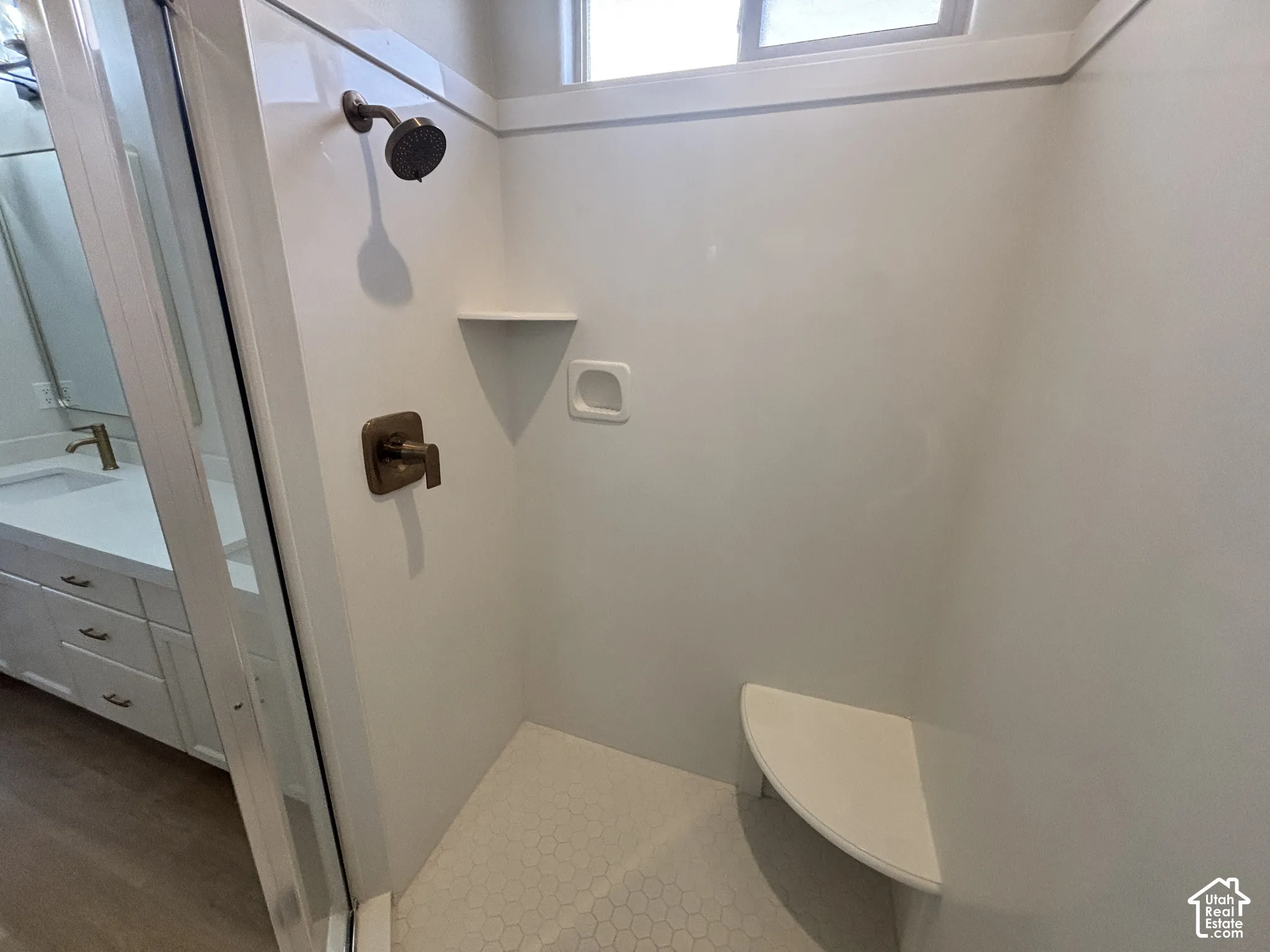 Walk-in shower with bronze-finish fixtures, a built-in corner seat, and a window