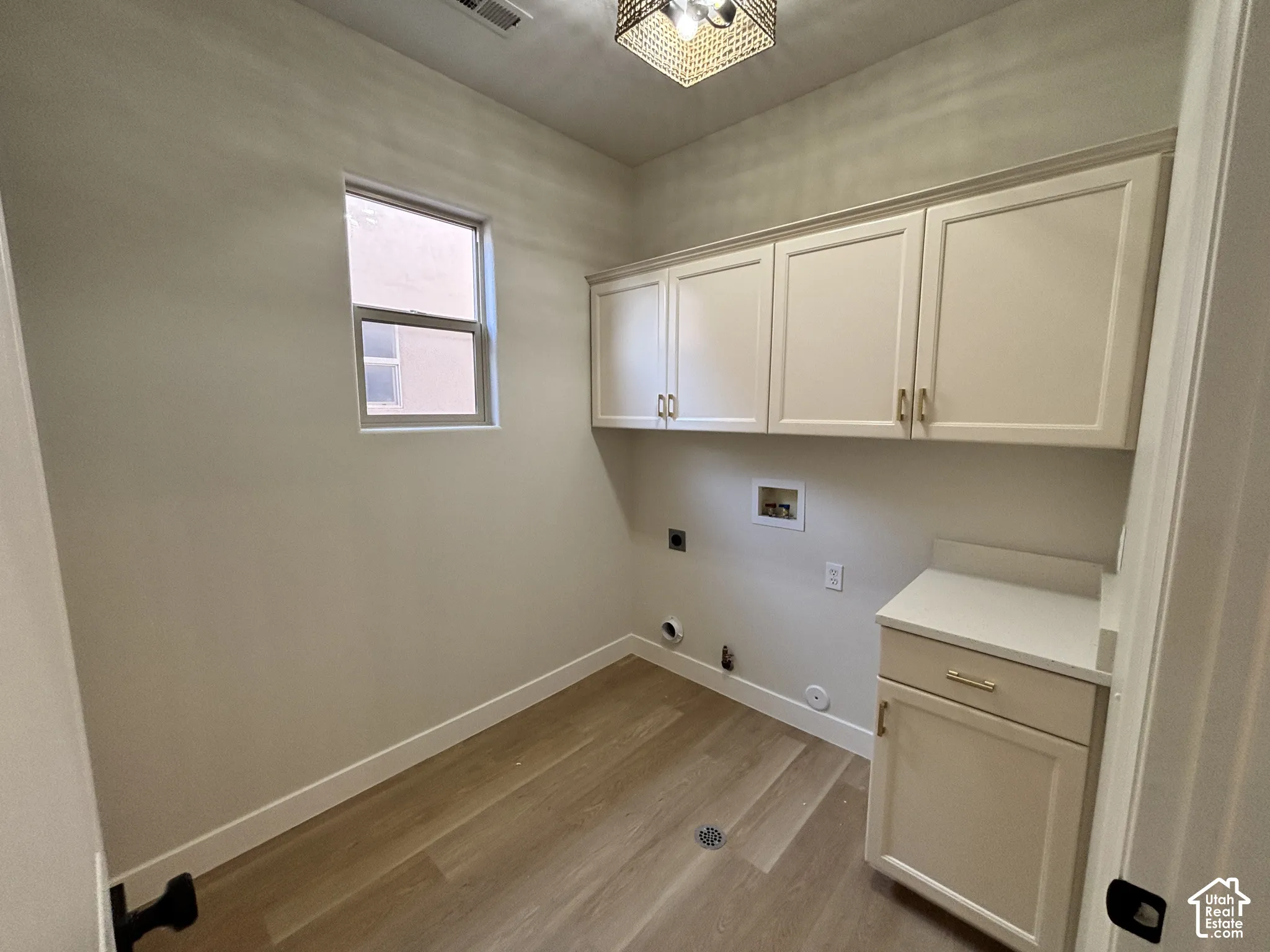 Built-in cabinetry with gold-finish hardware, light-toned wood-finish flooring, and a window for natural light