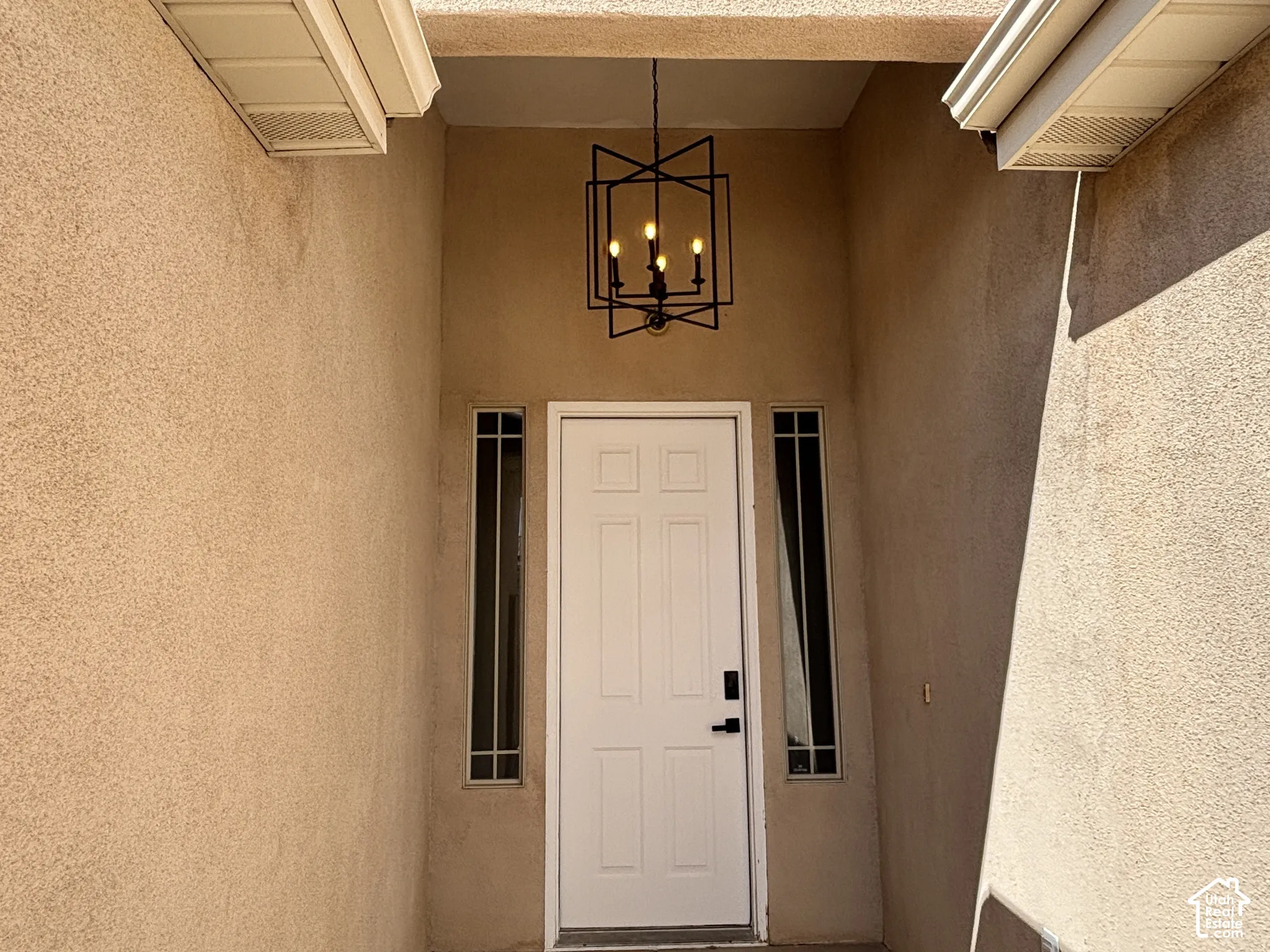 Entryway featuring a white paneled door, sidelight windows, and a black four-light chandelier