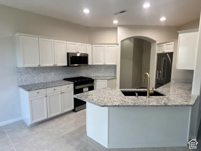 Kitchen featuring white cabinetry, granite countertops, stainless steel appliances, a tile backsplash, and recessed lighting