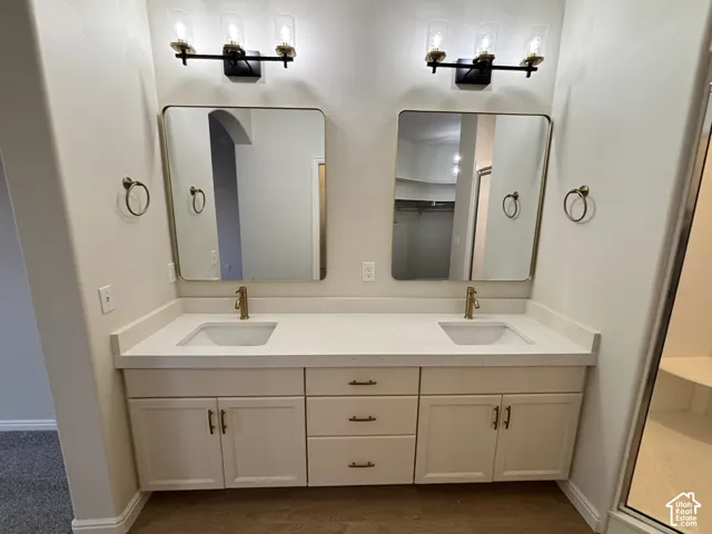 Dual vanity with integrated sinks, light-toned countertops, and gold-finish fixtures
