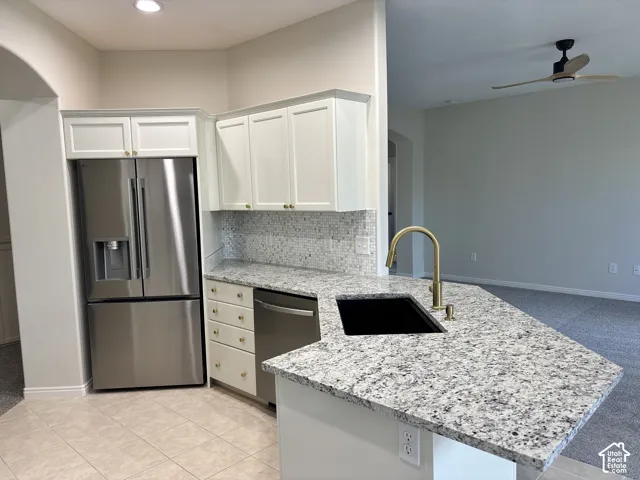 Kitchen featuring a stainless steel refrigerator, white cabinetry, granite countertops, and a tile backsplash