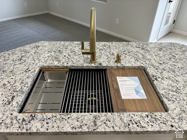 Granite countertop with an integrated workstation sink, featuring a gold-finish faucet and soap dispenser