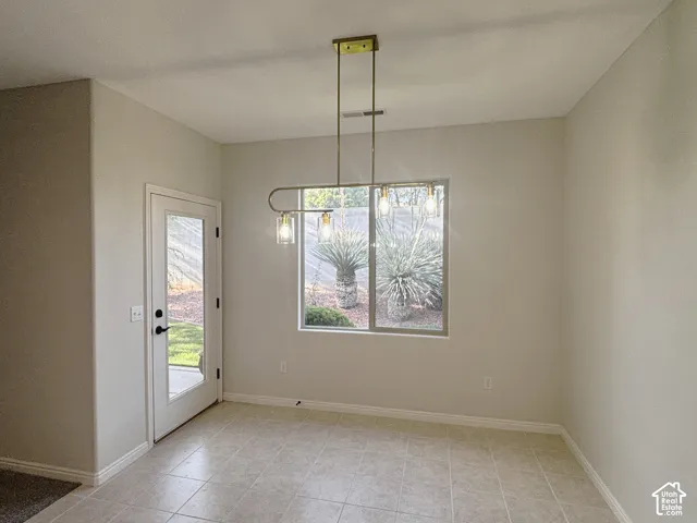 Tile flooring, modern linear pendant lighting, full-light exterior door, and a large window with exterior landscaping