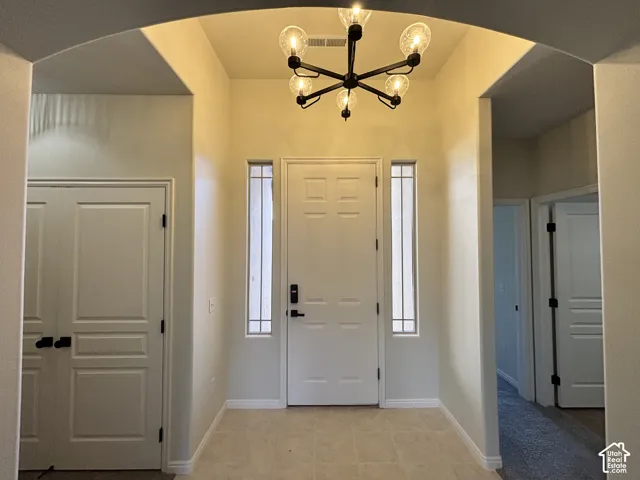 Foyer featuring an arched entryway, tile flooring, and a modern chandelier