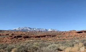 Expansive desert landscape with red rock formations and distant snow-capped mountains under a clear sky
