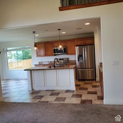 Kitchen featuring wood cabinetry, granite countertops, stainless steel appliances, and a central island with pendant lighting