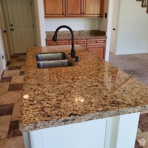 Kitchen island featuring a double basin stainless steel sink, dark bronze gooseneck faucet, and granite countertop