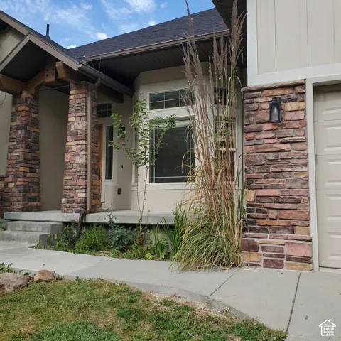 Stone veneer facade with an entry portico featuring timber accents, bay window, and exterior wall lantern