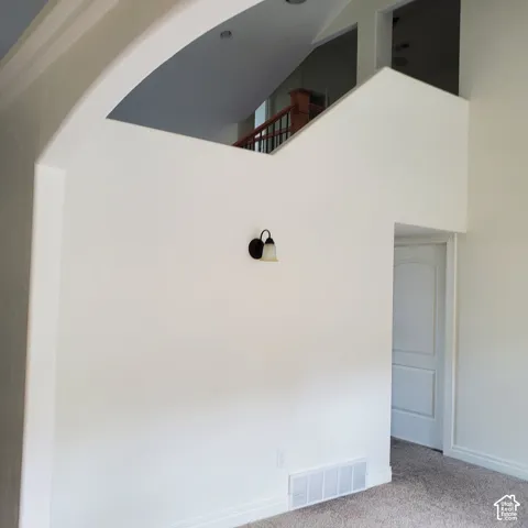Archway entrance featuring a wall sconce, textured carpeting, and white interior doors