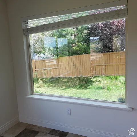 Expansive bay window with integrated blinds, offering natural light and a garden backdrop with a wood privacy fence