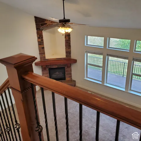 Living area featuring a floor-to-ceiling brick-surround fireplace with a wood mantle, a ceiling fan with integrated lighting, and multiple windows