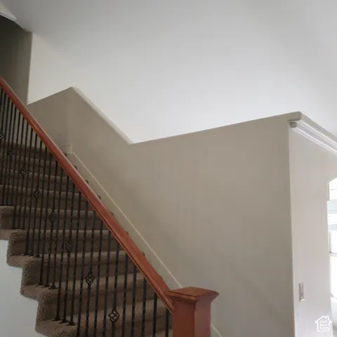 Staircase featuring a wood handrail, wrought iron balusters with decorative elements, and neutral-toned wall paint