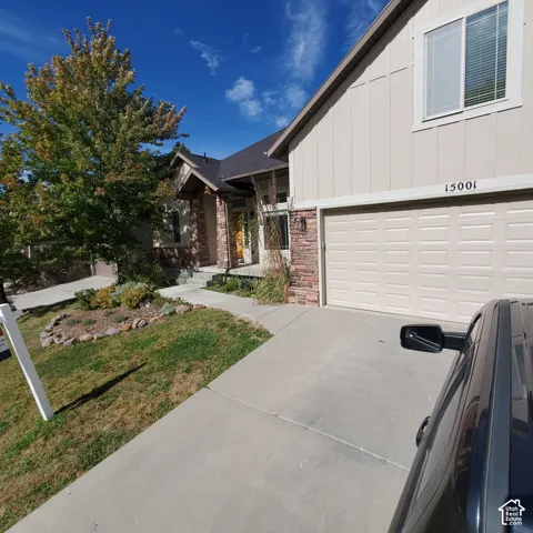 Exterior featuring stone accents, a two-car garage, a concrete driveway, and a front entry with an overhang