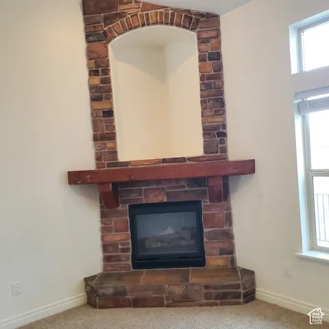 Corner fireplace featuring a natural stone facade, wood mantel, and integrated media niche