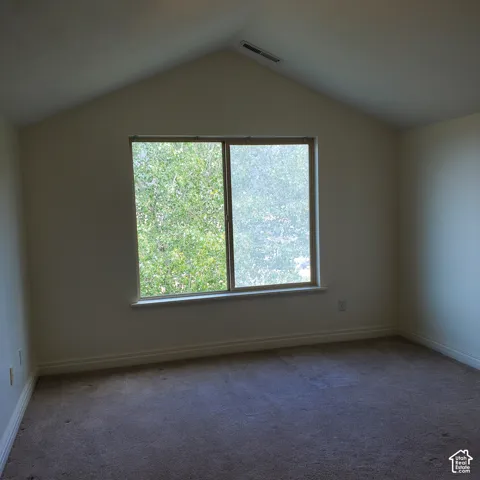 Vaulted ceiling, wall-to-wall carpeting, and a window with exterior tree scenery