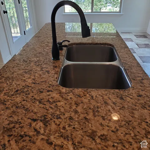 Granite countertop with an undermount double-basin stainless steel sink and a matte black gooseneck faucet