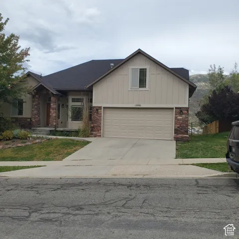 Siding exterior with stone accents, a two-car garage, and a concrete driveway