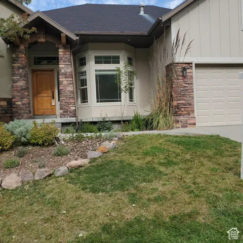 Bay window, stone veneer accents, wood entry door, and an attached garage