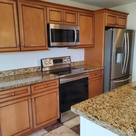 Stainless steel appliances, built-in microwave, wood cabinetry, granite countertops, and tile flooring