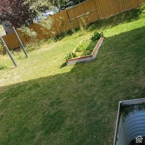 Expansive lawn area featuring a raised garden bed and wood privacy fencing