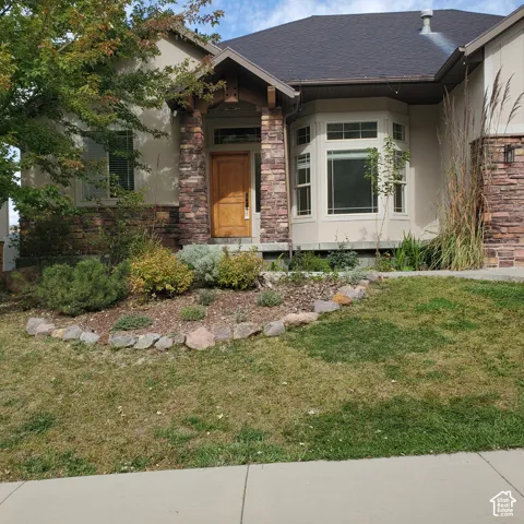 Stucco exterior with stone accents, wood front door, and bay window