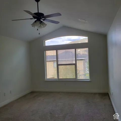Vaulted ceiling with an arched transom window, large window with blinds, ceiling fan with integrated lighting, and recessed lighting