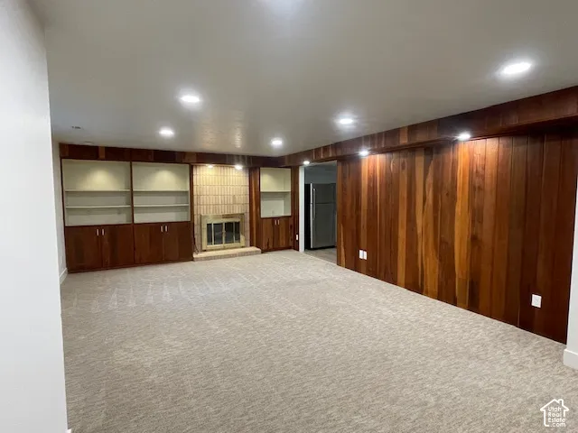 Recessed lighting illuminates the carpeted flooring and wood-paneled walls
