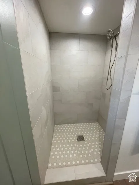 Shower enclosure with tiled walls, round penny tile flooring, and a rainfall showerhead
