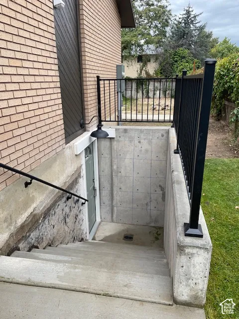 Brick exterior with concrete stairs leading to a below-grade entry