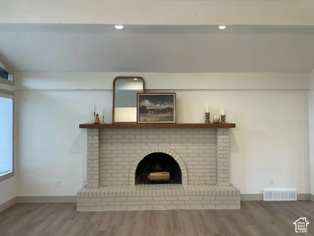 Brick fireplace with an arched firebox, a wood mantel, and wood-finish flooring