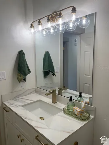 Vanity featuring an integrated rectangular sink, gold-tone faucet, and white countertop with veining