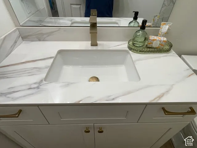Vanity with a rectangular undermount sink, brass-finish faucet, and white countertop with veining