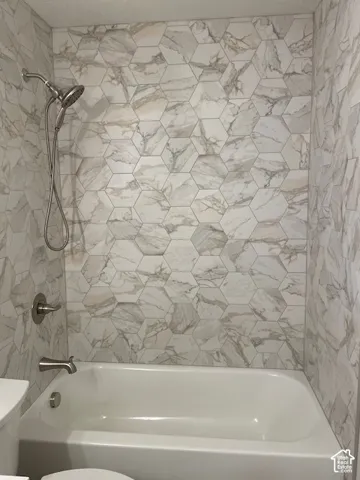 Hexagonal tile shower surround, integrated bathtub, and brushed nickel fixtures