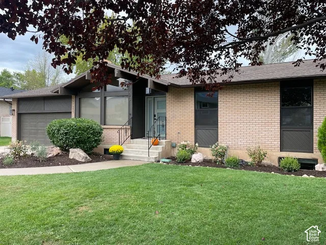 Brick exterior with a peaked roofline, front entry steps, and an attached garage