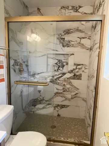 Frameless shower enclosure with a gold-tone trim and handle