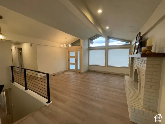 Vaulted ceiling with recessed lighting, wood-finish flooring, and a painted brick fireplace