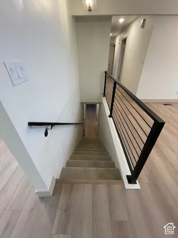 Laminate wood-finish flooring, carpeted staircase, and modern horizontal baluster railing