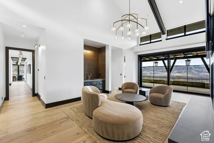 Vaulted ceilings with exposed beams, wood-finish flooring, a built-in wet bar, and large sliding glass doors