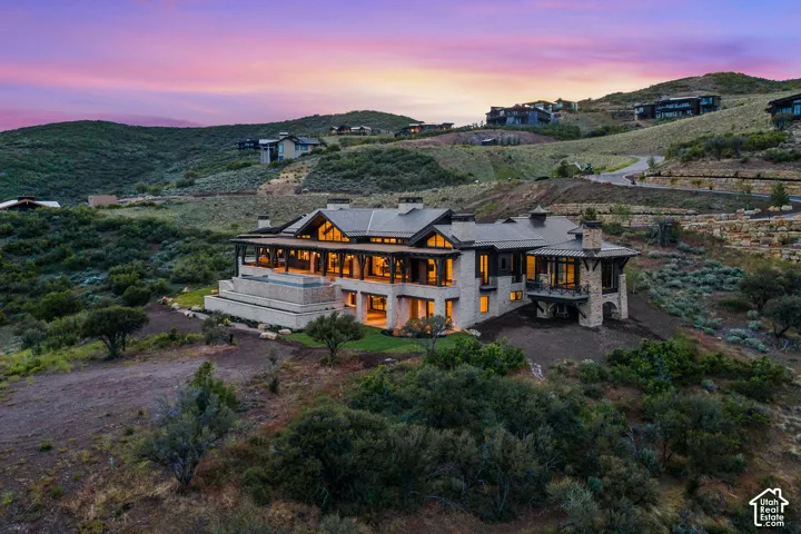 Stone and wood-clad exterior with multiple levels, expansive exterior decking, and a covered balcony