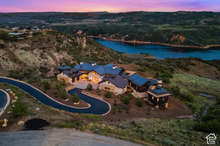 Expansive property featuring a multi-level structure, a dark asphalt driveway, natural stone accents, and a tiered architectural design