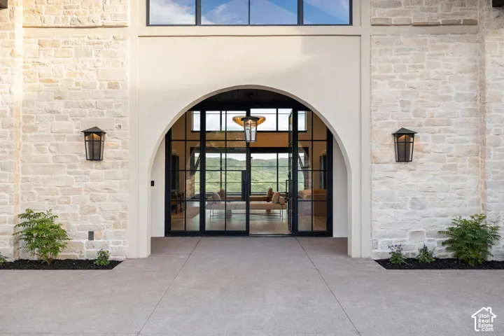 Stone exterior facade with an arched entry, black-framed glass doors, and integrated lighting fixtures