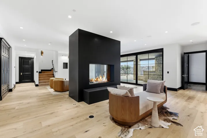 Spacious interior featuring wide plank wood-finish flooring, a contemporary fireplace with a sleek black surround, and large sliding glass doors