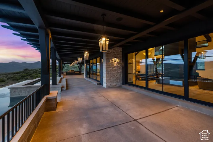 Covered patio with an infinity-edge pool, stone-clad exterior, and expansive floor-to-ceiling windows